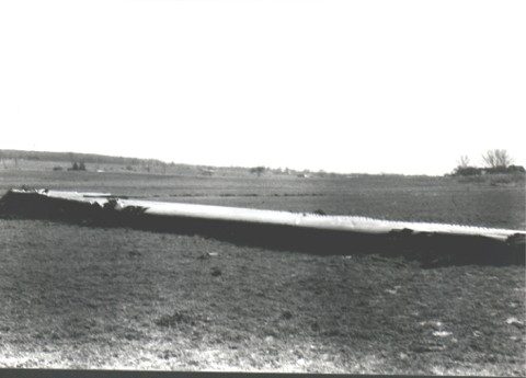A further view of scattered wreckage across the farmland.